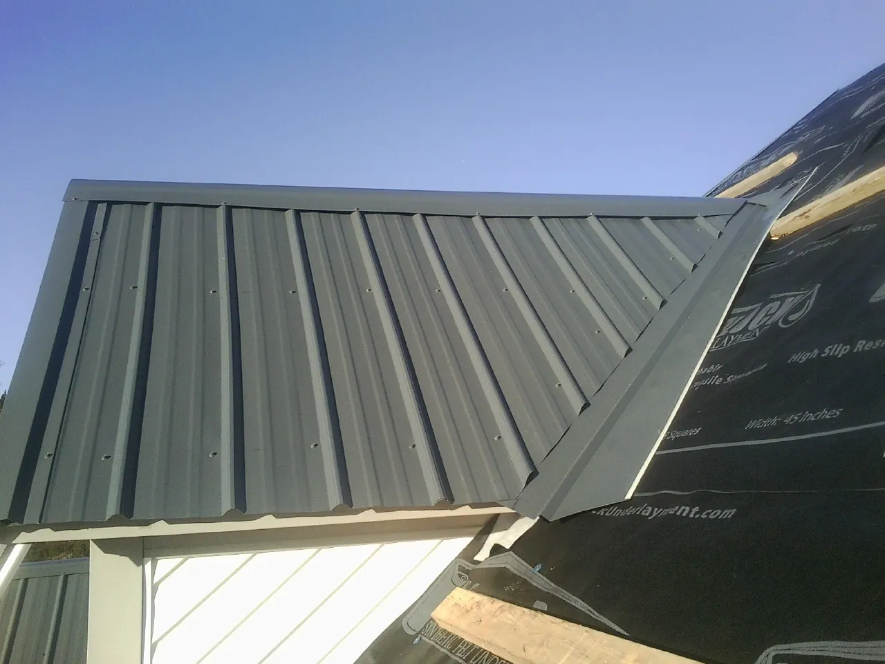 Gray metal roof panels going on over a garage gable in Coulee Dam