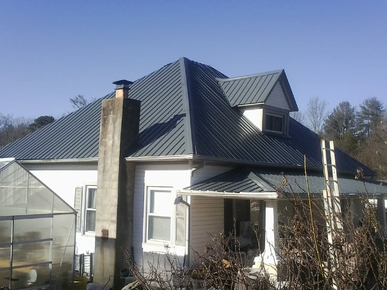 Dark blue standing seam metal roof on a white farmhouse with dormer — Slate & Tile Roof Repair by Roofing Brothers in Coulee Dam