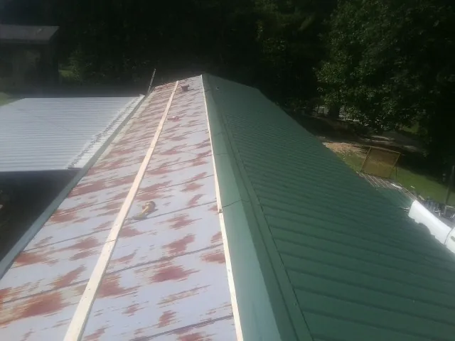 Old rusted panels beside newly installed green metal roofing — Wind Damage Roof Repair by Roofing Brothers in Coulee Dam