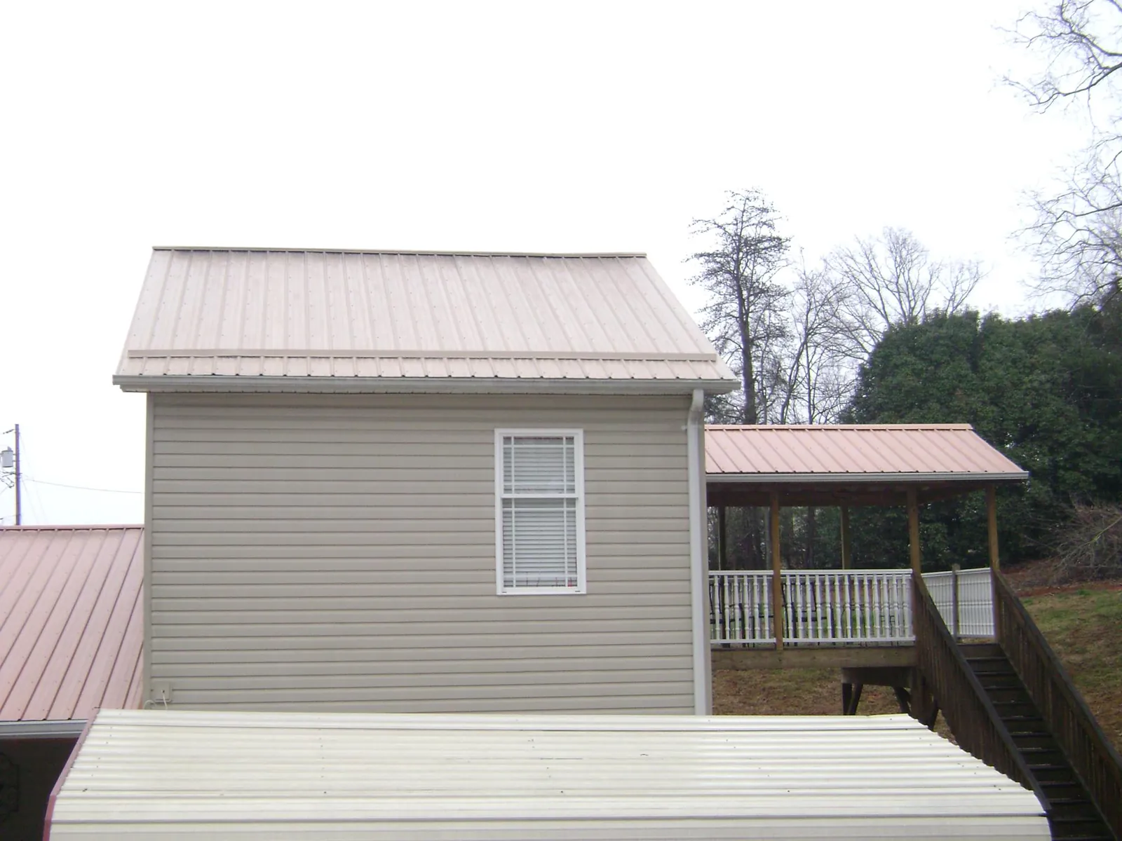 Tan metal roofs on a two story addition and attached porch, from a Roof Replacement job in Coulee Dam