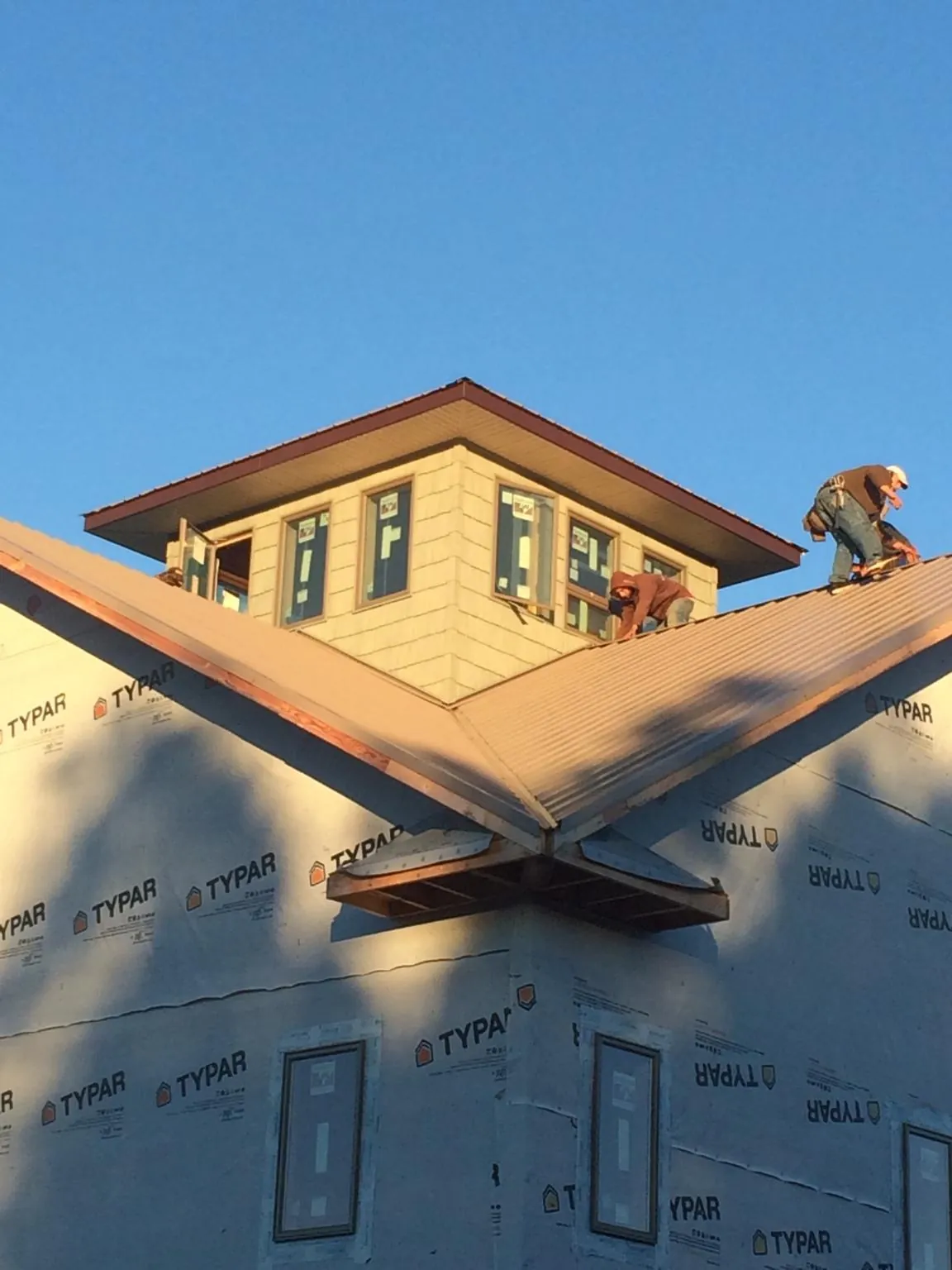 Roofers working around a rooftop cupola on a new metal roof at sunset — Roof Waterproofing in Coulee Dam by Roofing Brothers